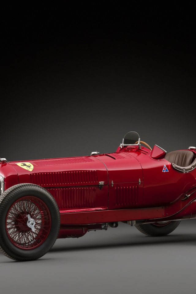 Красный ретро автомобиль Alfa Romeo на сером фоне