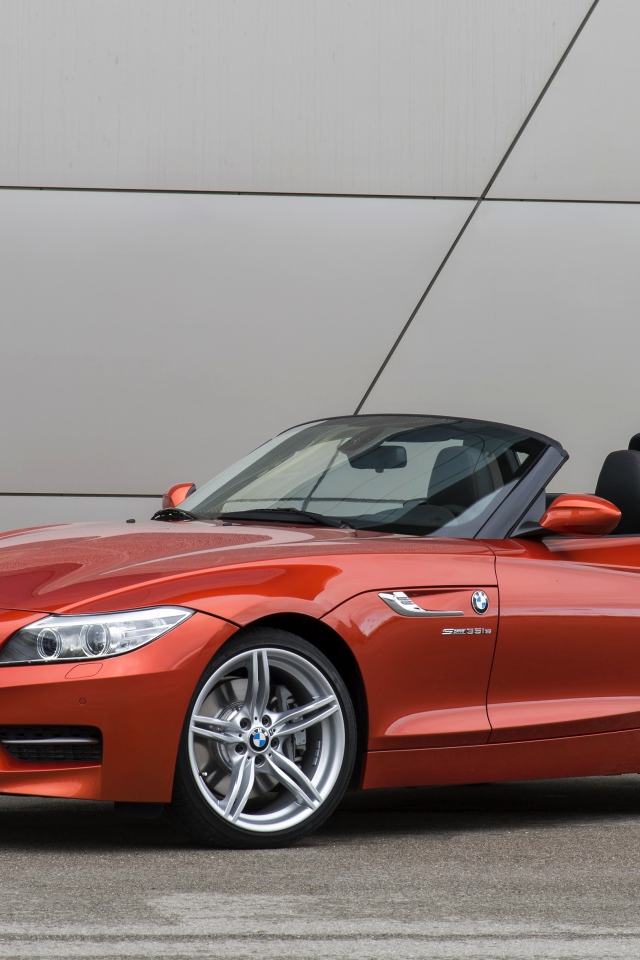 Оранжевый автомобиль кабриолет BMW Z4 на фоне стены