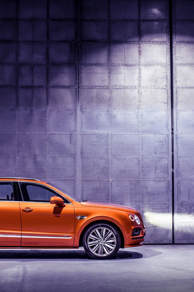 Оранжевый автомобиль Bentley Bentayga вид сбоку