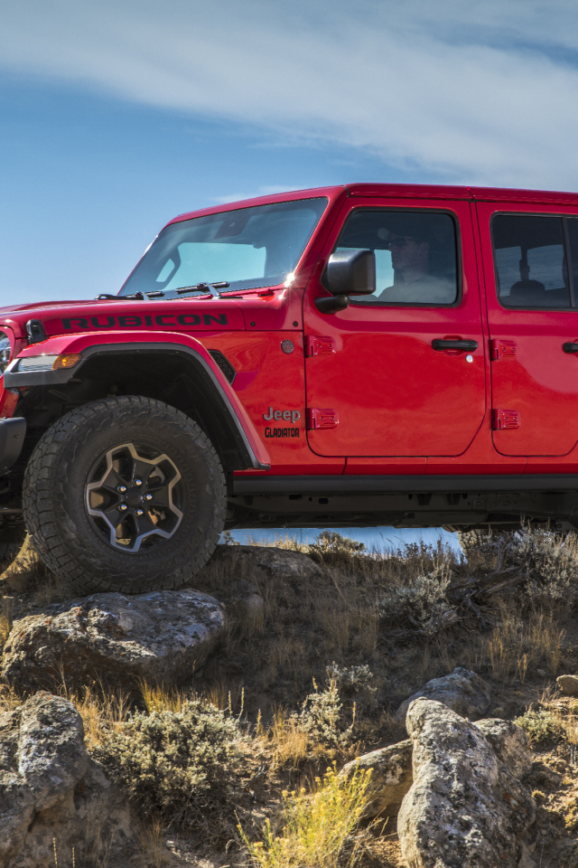 Красный пикап Jeep Gladiator Rubicon на холме с камнями