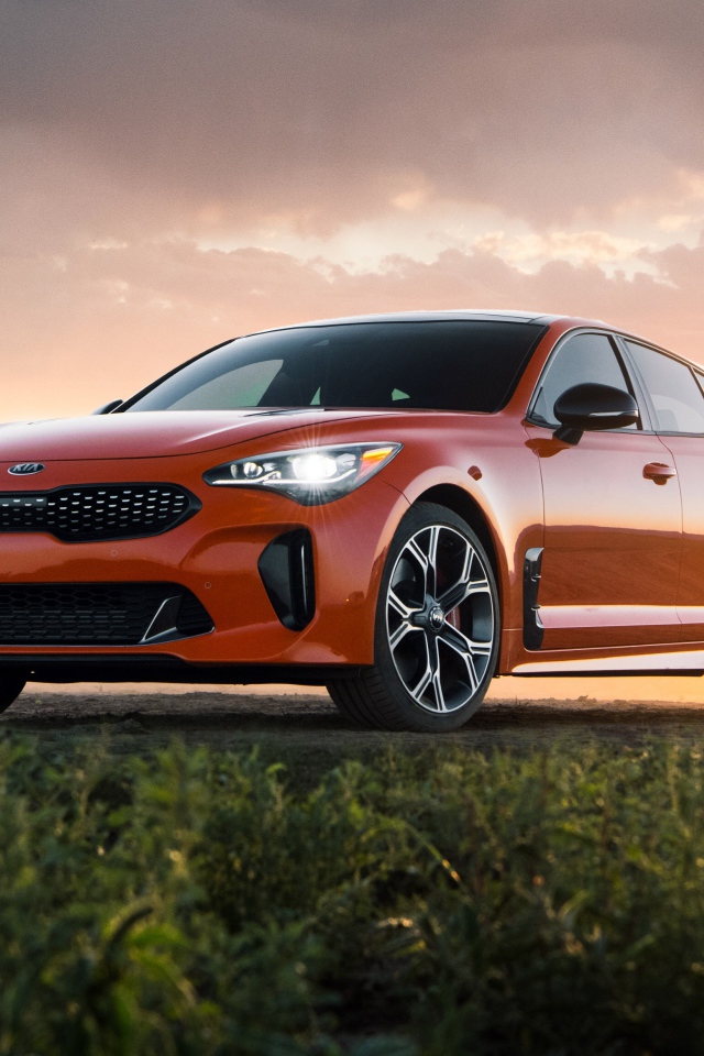 Оранжевый автомобиль  Kia Stinger GTS, 2020 года на закате