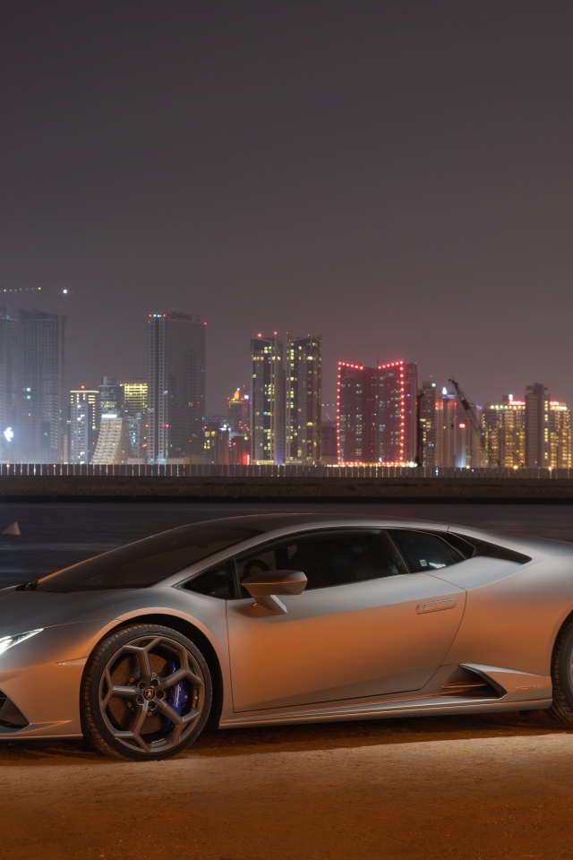 Серебристый автомобиль Lamborghini Huracan Evo на фоне города