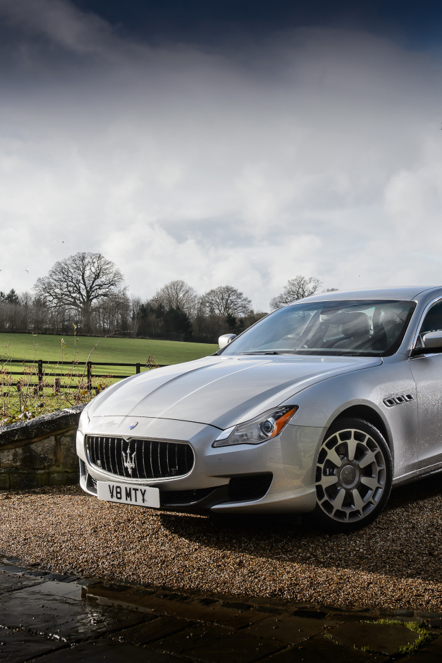 Серебристый стильный дорогой автомобиль Maserati Quattroporte на дороге после дождя