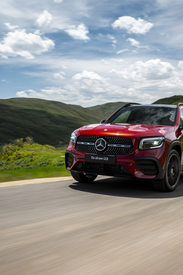 Красный автомобиль Mercedes-Benz GLB-Class  на фоне зеленых холмов