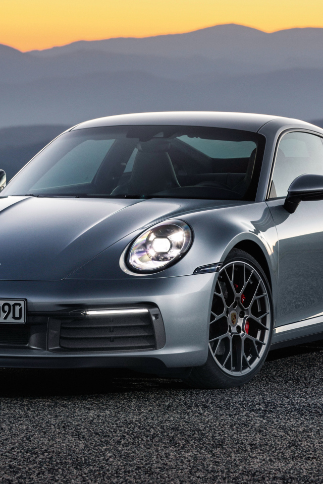 Серебристый автомобиль Porsche 911 Carrera 4S 2019 года на фоне гор 