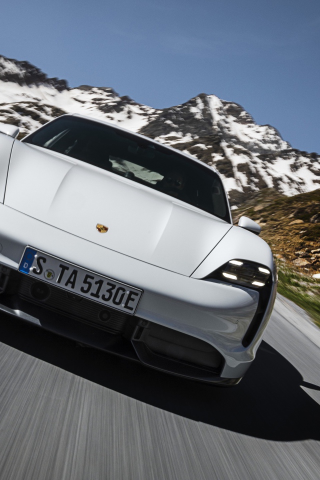 Белый автомобиль Porsche Taycan Turbo S 2019 года на фоне заснеженных гор