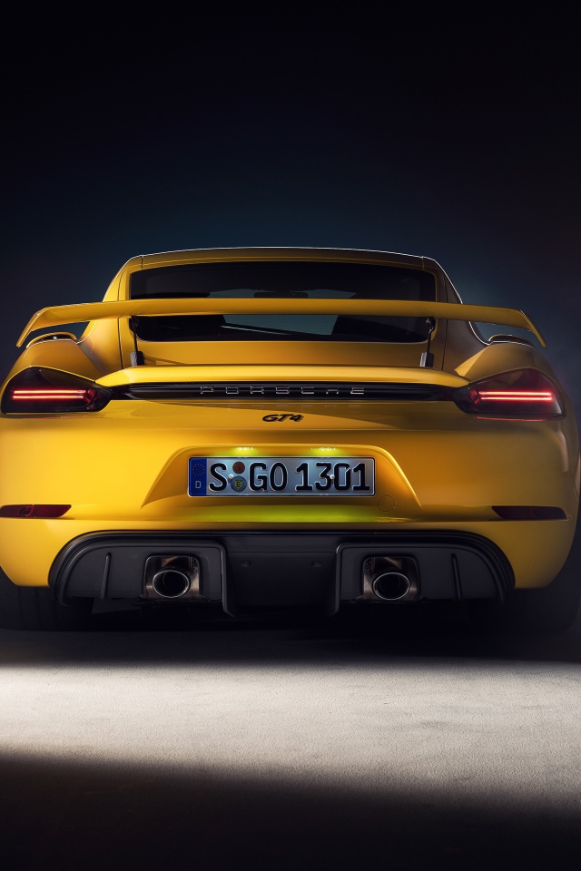 Желтый автомобиль Porsche 718 Cayman GT4, 2019 года вид сзади на сером фоне