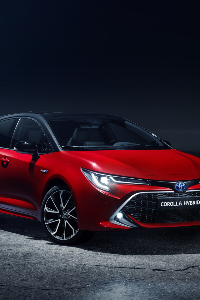 Красный автомобиль Toyota Corolla Hybrid 2018 года в свете фонарей