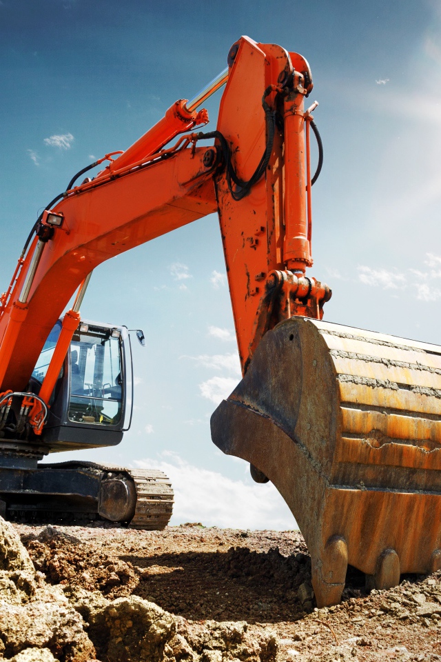 Экскаватор с ковшом на фоне голубого неба