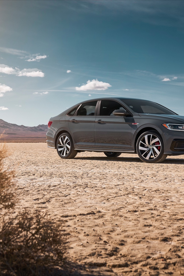 Стильный серебристый автомобиль Volkswagen Jetta на фоне неба 