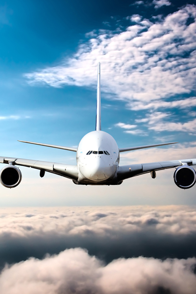 Самолет в белых облаках на фоне голубого неба
