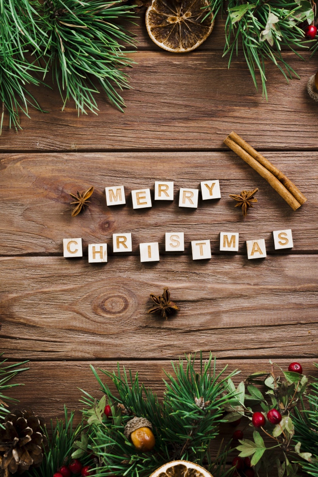 Надпись Merry Christmas на деревянном столе с еловыми ветками 