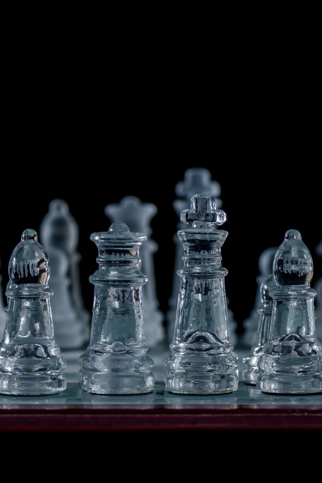 Стеклянные шахматы на доске на черном фоне