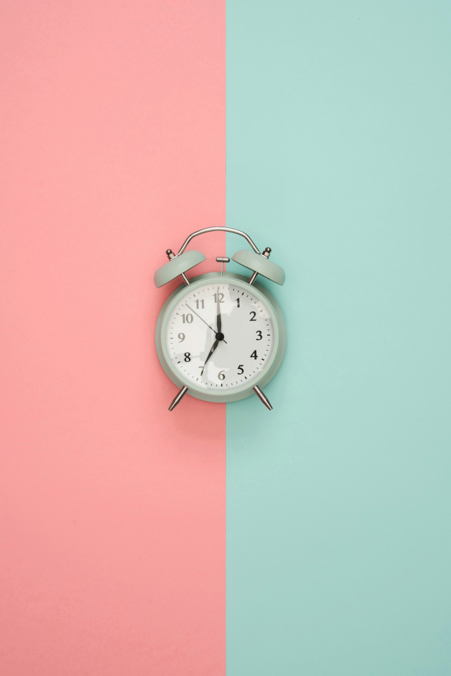 Серый будильник на разноцветном фоне