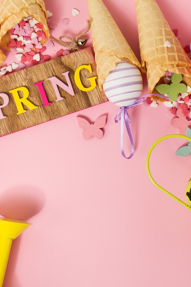 Надпись весна с вафельными рожками и яйцами на розовом фоне