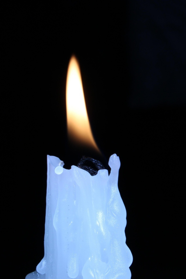 Зажженная свеча на черном фоне