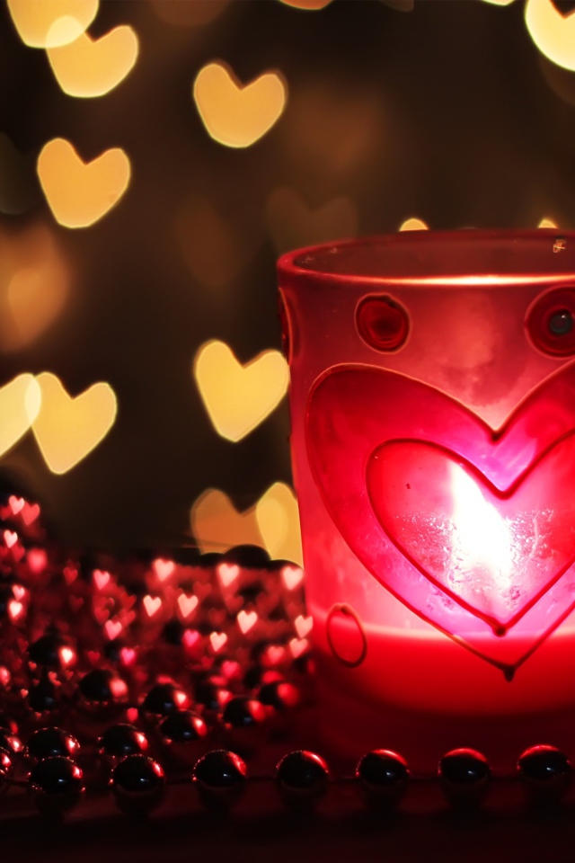 Зажженная свеча на столе с бусами 