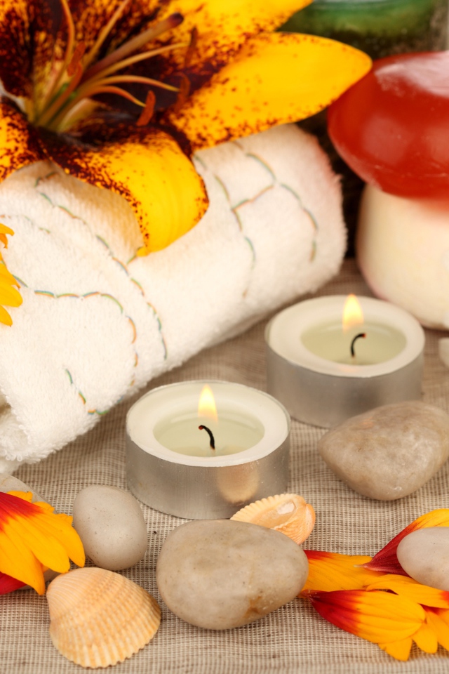 Зажженные свечи на столе с полотенцем, цветами и мылом