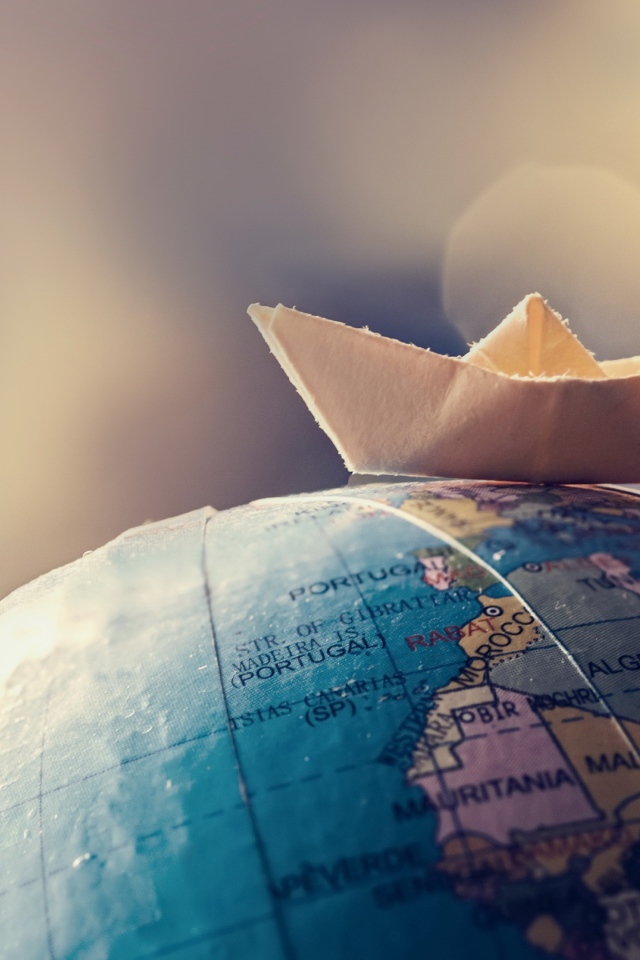 Бумажный кораблик лежит на глобусе