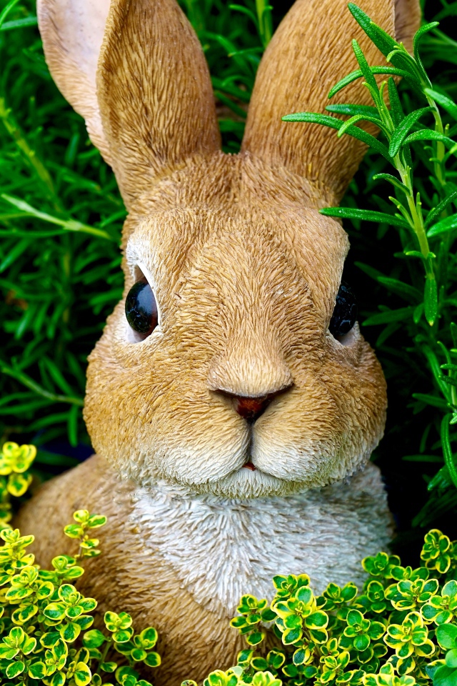 Статуэтка кролика в зеленой траве 