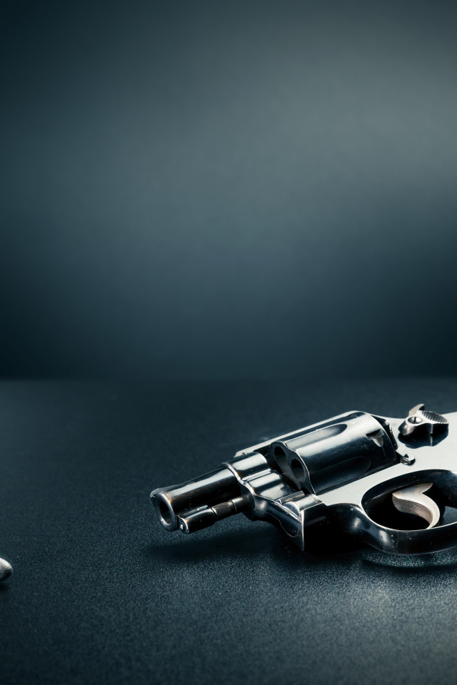 Револьвер с пулями на сером фоне