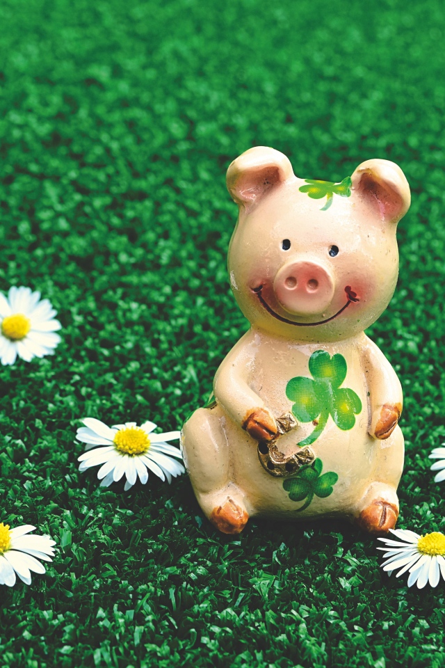 Статуэтка поросенка на зеленой траве с ромашками