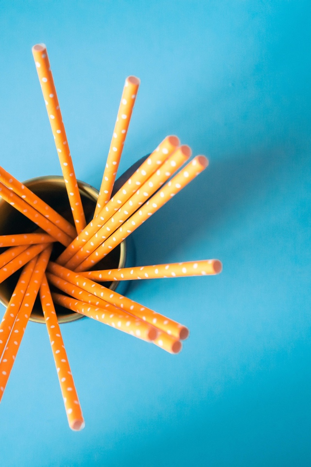 Трубочки в стакане на голубом столе