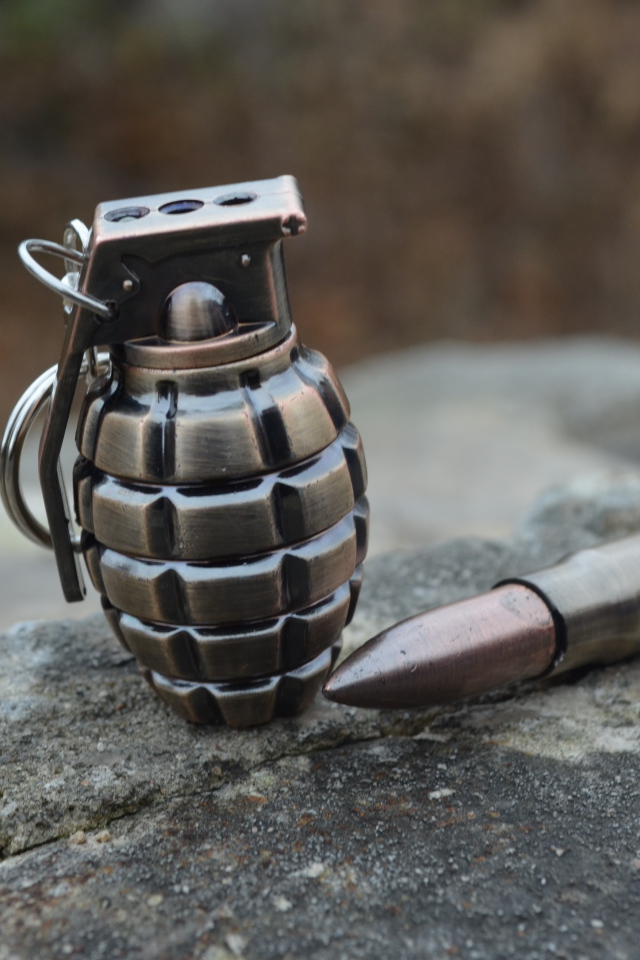 Боевая граната с патроном лежат на камне 