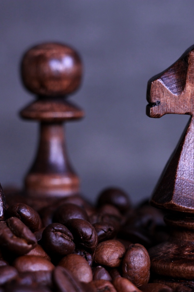 Деревянные шахматные фигуры стоят на кофейных зернах 