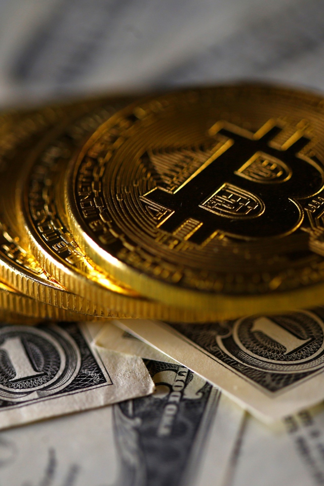Монеты Биткоин лежат на купюрах по одному доллару