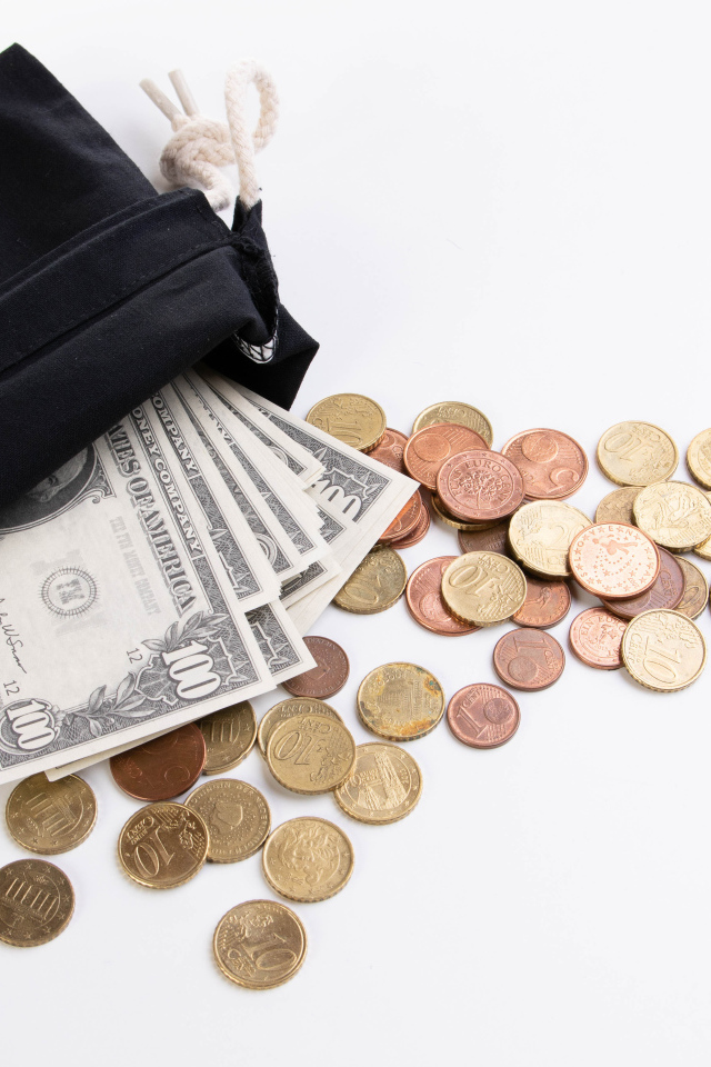 Кошелек с монетами и долларами на белом фоне