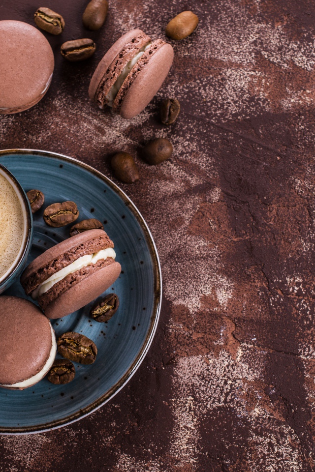 Чашка кофе с шоколадными макарунами на столе