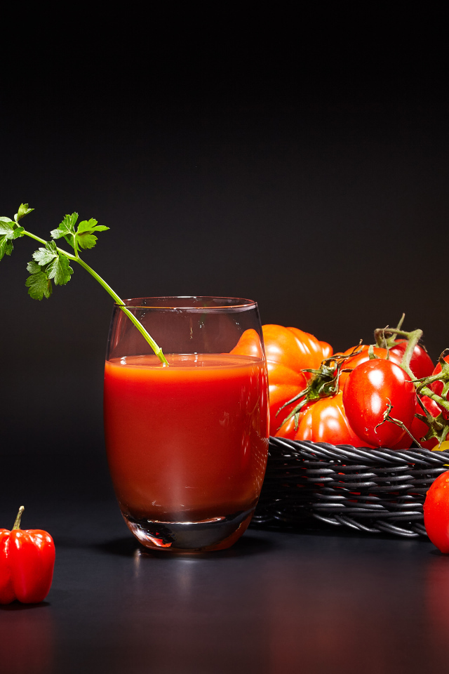 Стакан томатного сока на столе с помидорами