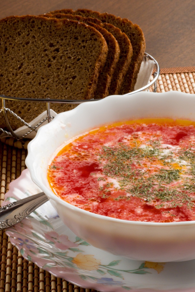 Тарелка красного борща на столе с сыром и черным хлебом