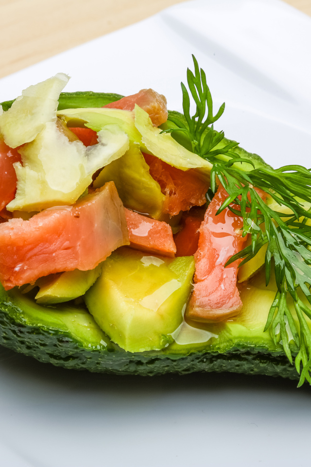 Авокадо с салатом из красной рыбы на белой тарелке