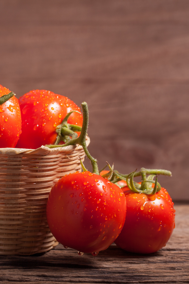 Красивые красные мокрые помидоры в корзине на столе 