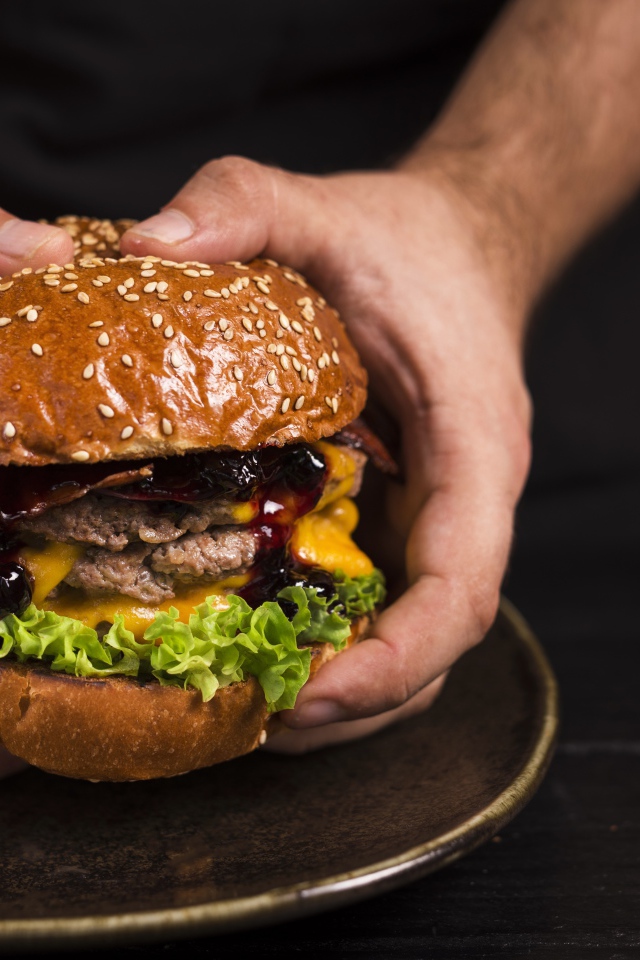 Большой сочный гамбургер в руках