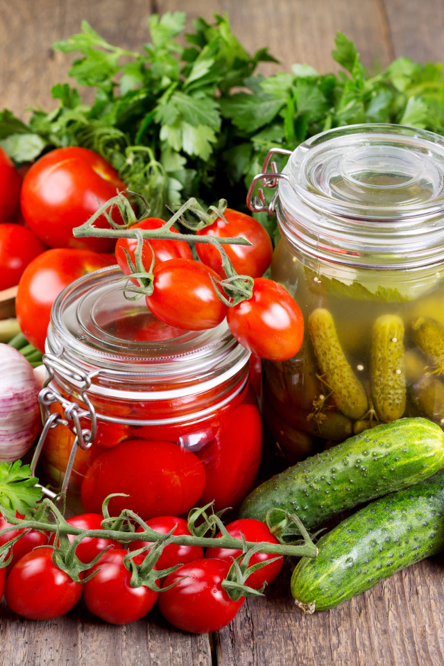 Консервированные помидоры и огурцы на столе со свежими овощами и зеленью 