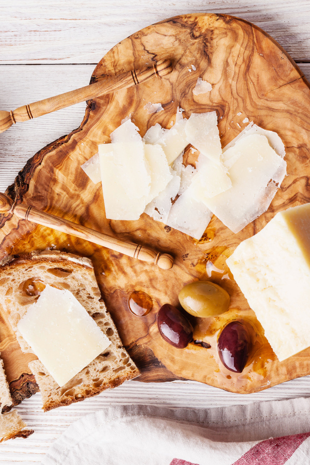 Сыр на доске с хлебом и и оливками