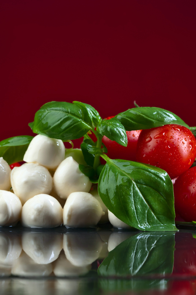 Сыр на столе с зеленью базилика и красными помидорами