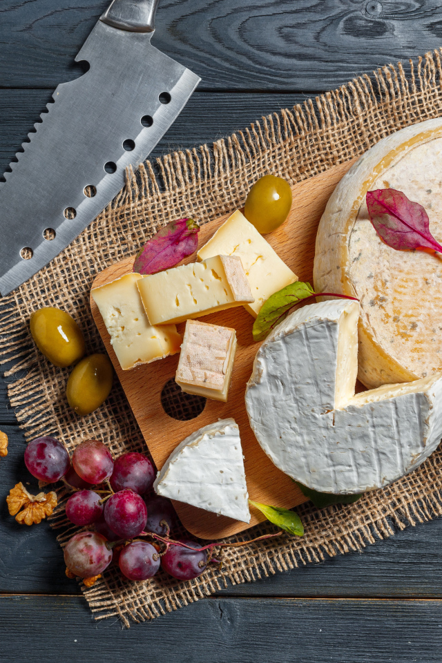 Сыр с плесенью на столе с орехами и виноградом 