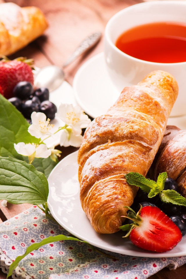 Круассаны на столе с ягодами и чашкой чая