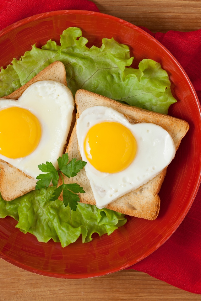 Гренки с яичницей на тарелке с листьями салата 