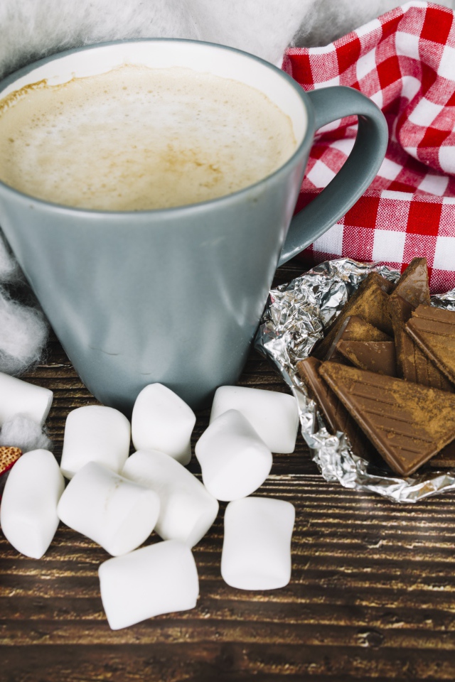 Чашка кофе на столе с маршмеллоу и шоколадом