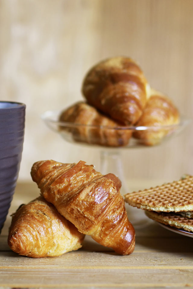 Чашка на столе с круассанами и вафлями 