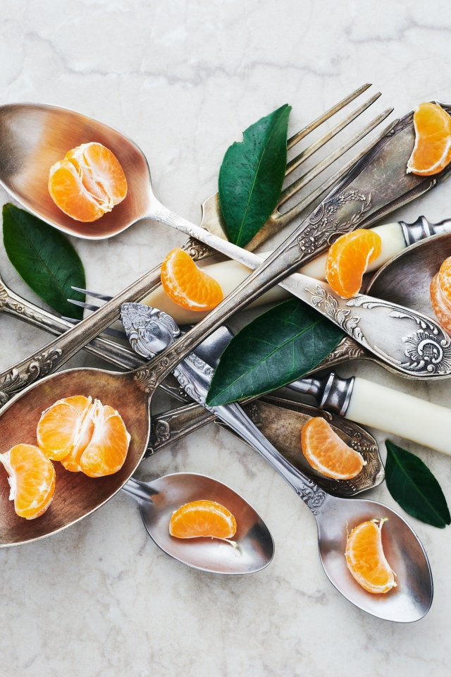 Столовые приборы на столе с дольками мандарина