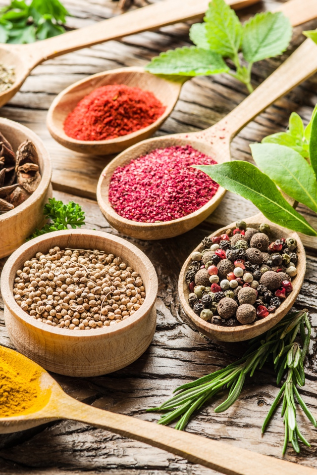 Разные специи в деревянных ложках на столе 