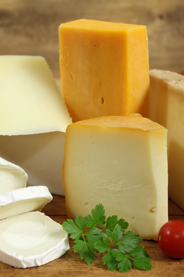 Разные виды твердого сыра на столе с помидорами и петрушкой
