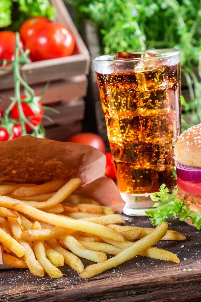 Картофель фри, гамбургер, кола и помидоры на столе