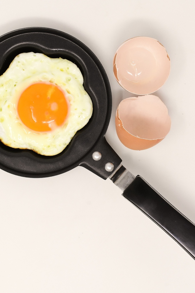 Яичница на сковороде на сером фоне со скорлупой